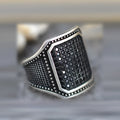 Black alloy ring with copper inlaid detail around a central zircon stone.