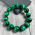 Natural green tiger eye stone bracelet with geometric polished beads on a wrist.