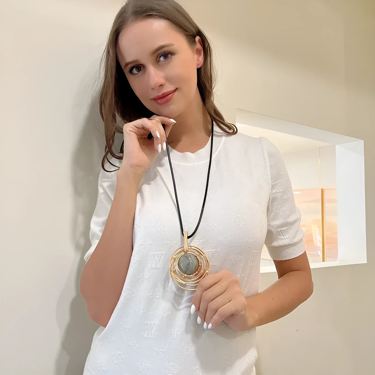 Gold geometric alloy pendant on a brown snakeskin wax rope chain necklace laid flat.