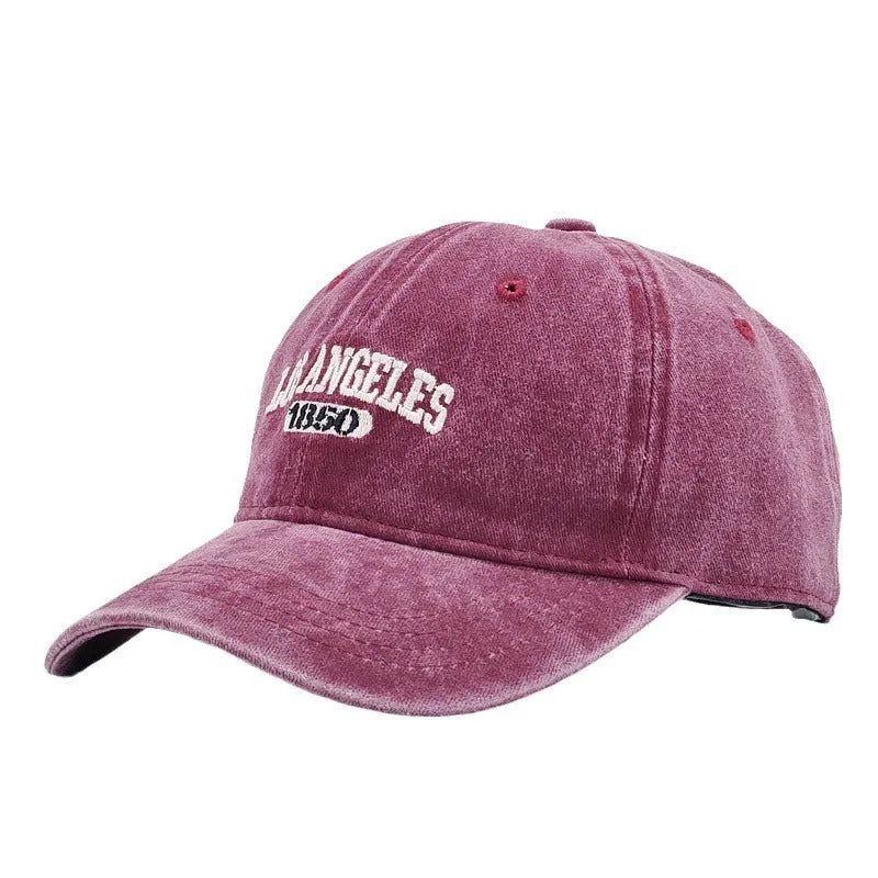 Retro style peaked cap with embroidered distressed letters on the front, shown in beige colour.
