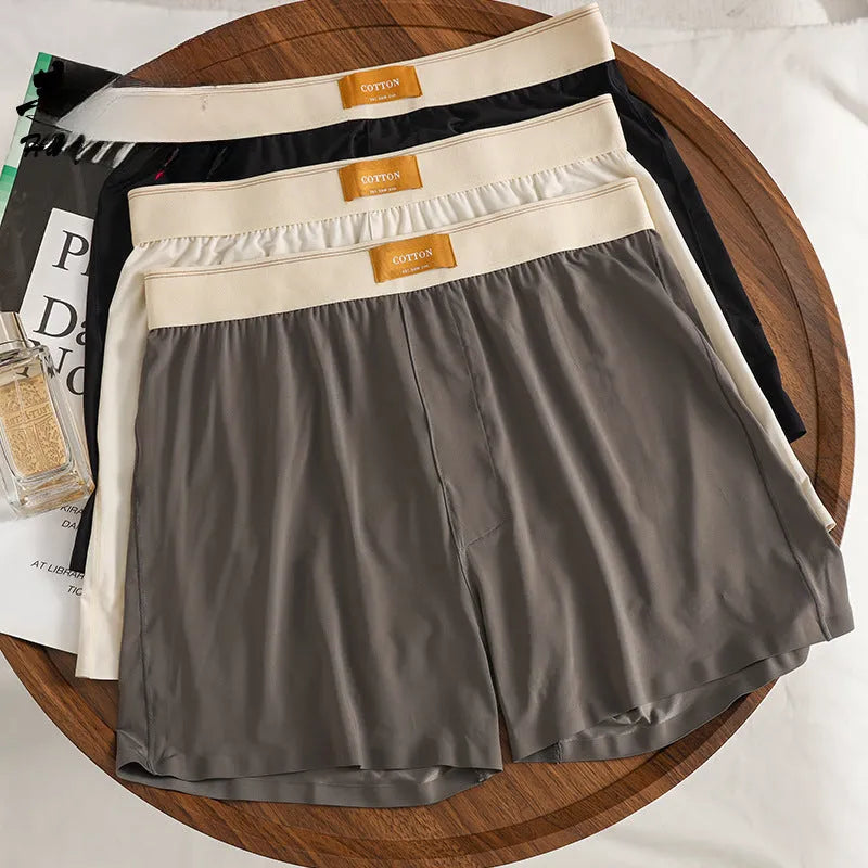 Three pairs of men's solid colour ice silk briefs on a grey background.