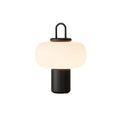 Minimalist clear glass bedside table lamp with warm white light on a wooden surface.