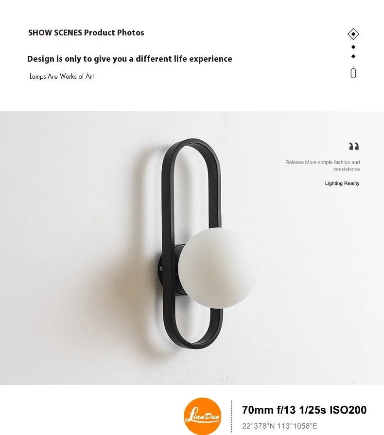 Minimalist modern wall lamp with glass shade and iron body in black finish, mounted on a wall.