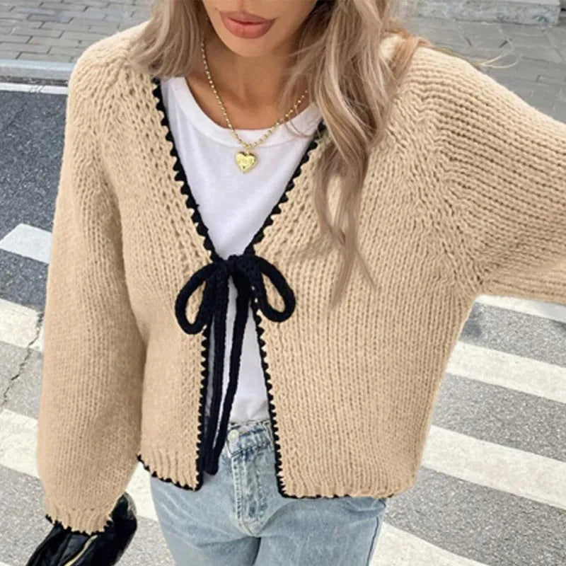 Gray lace-up front cardigan with crocheted flower detail on a model, showing loose long sleeves.