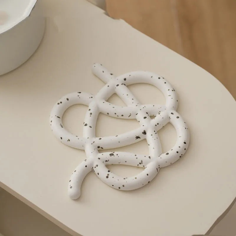 Irregular shaped solid colour ceramic heat proof placemat on a wooden table