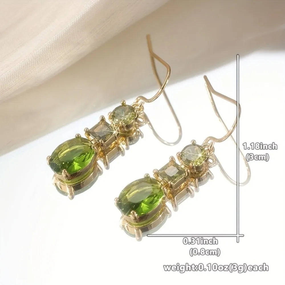 A pair of green square-shaped geometric copper drop earrings on a plain background.