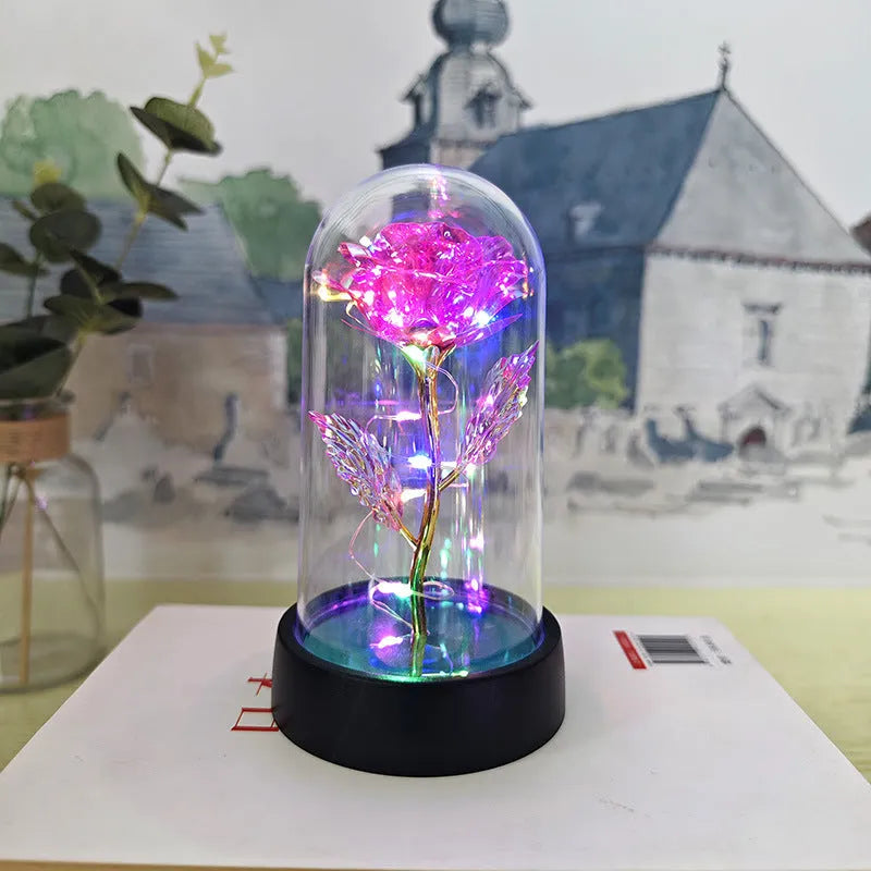 Small decorative night lamp with glass cover and plastic flowers, showing coloured light illumination.
