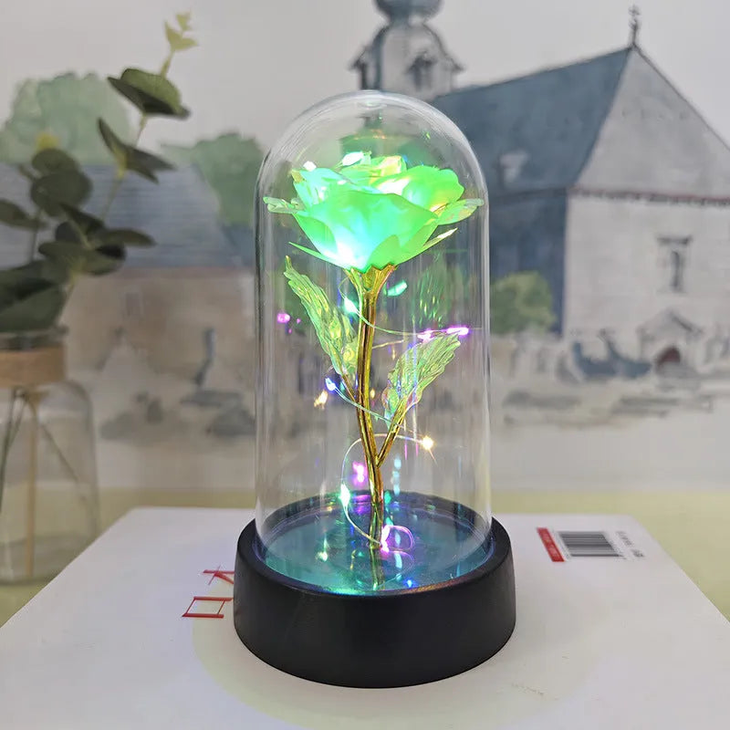 Small decorative night lamp with glass cover and plastic flowers, showing coloured light illumination.