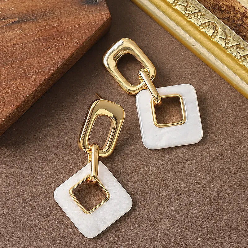 Pair of hollow square earrings with bevelled corners in a metallic finish, shown on a white background.