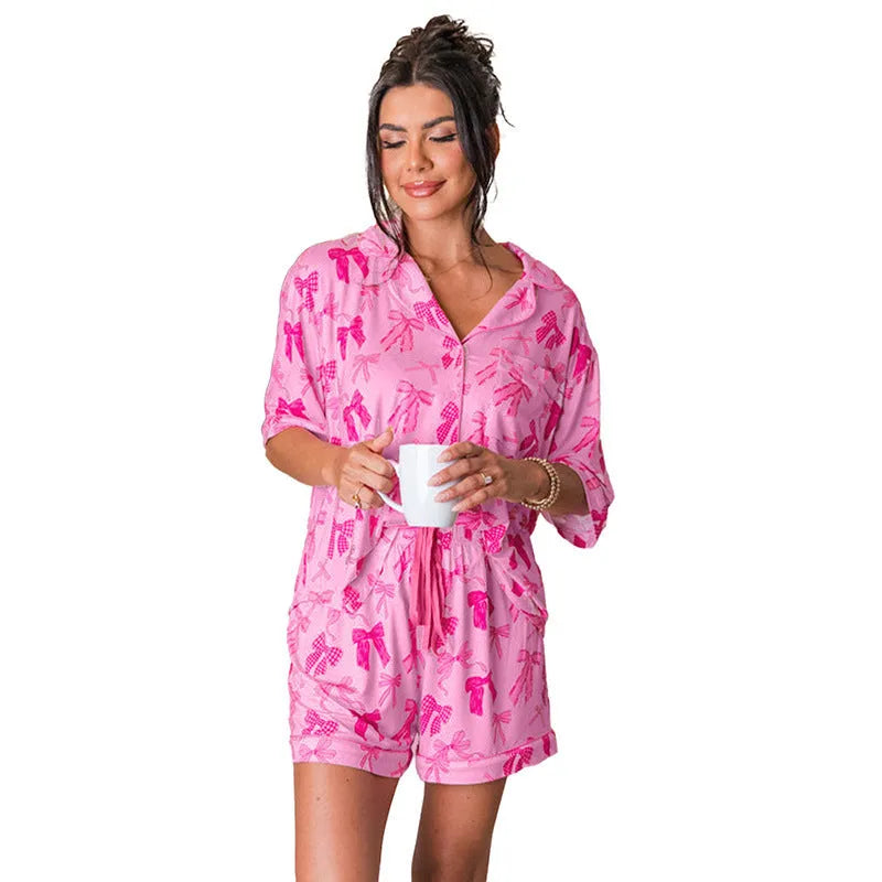 Pink women's pajama set with bow print, featuring a short-sleeved top and elasticated waist trousers.