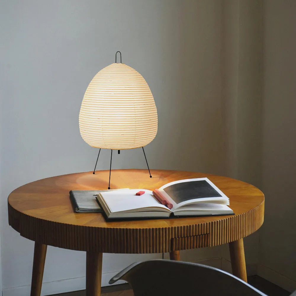 Japanese style table lamp with a white rice paper lantern shade and a silver aluminium base on a wooden table.