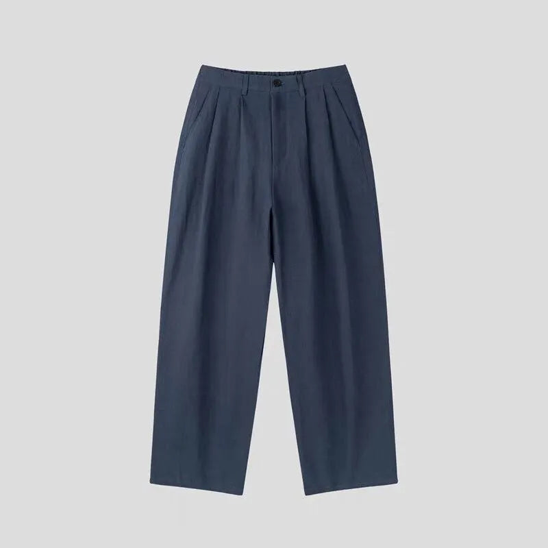 Men's apricot coloured loose-fit cotton linen trousers with a pencil leg on a plain background