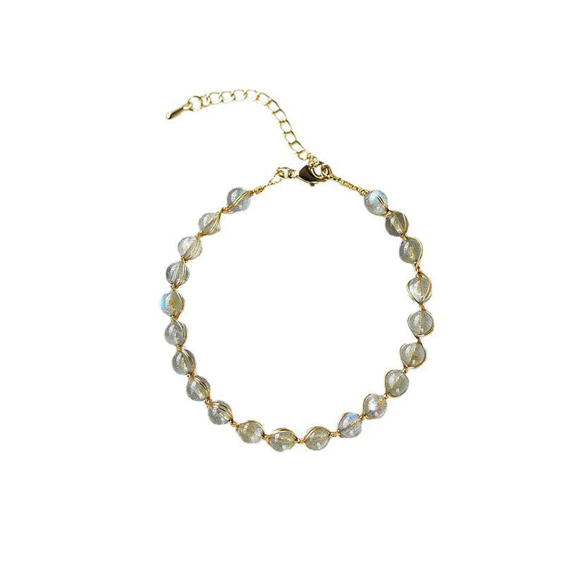 Blue moonstone and gold tone bracelet with 6mm beads on a wrist.