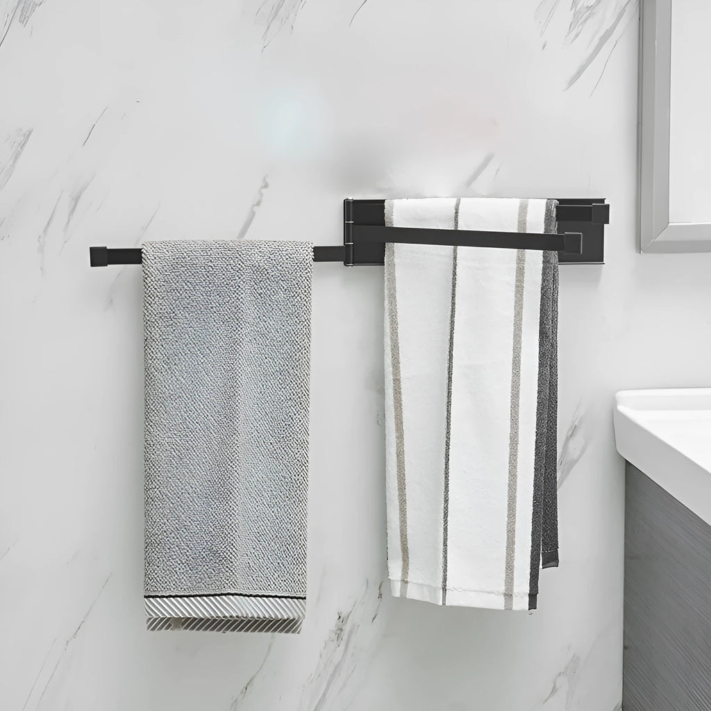 Black folding towel rack mounted on a bathroom wall with towels hanging, showing its no-drill installation.