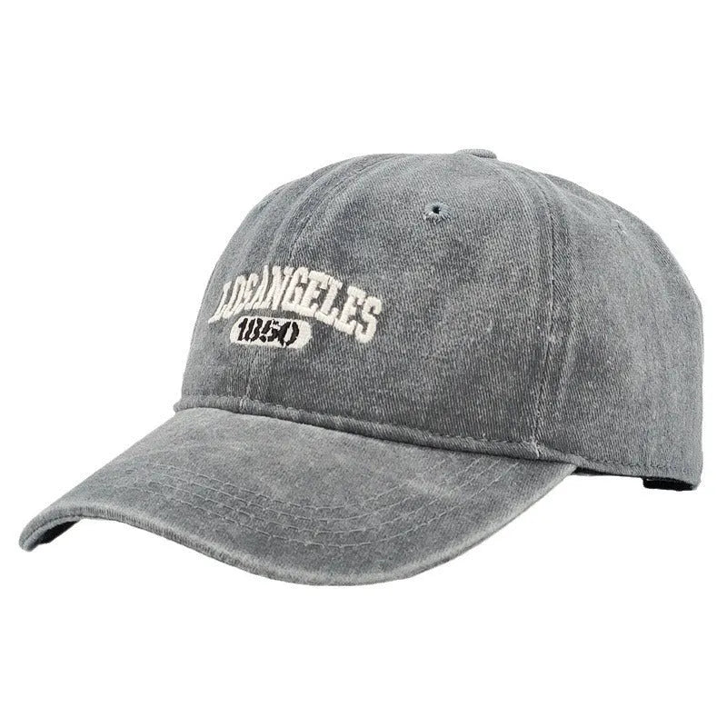 Retro style peaked cap with embroidered distressed letters on the front, shown in beige colour.
