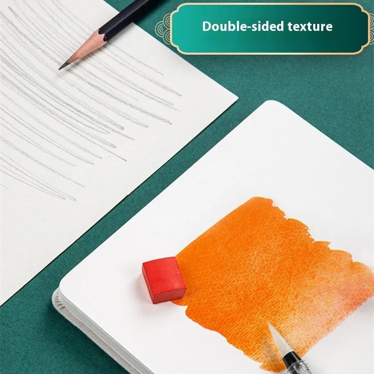 Feiluniao fabric cover watercolour notebook open on a table with brushes, 185mm length