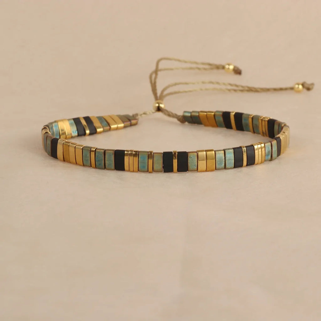Geometric glass beaded bracelet in milky white, black, green, blue, or red on a white background.
