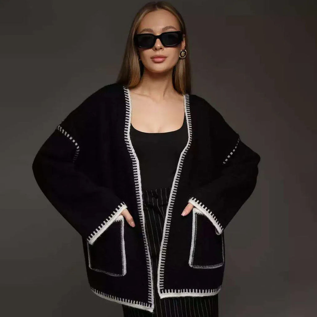 Loose grey knitted cardigan with lace-up front ties on a hanger.