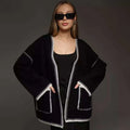 Loose grey knitted cardigan with lace-up front ties on a hanger.