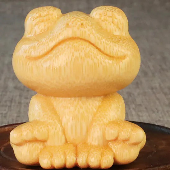 Solid bamboo carving ornament of a smiling frog cartoon character.