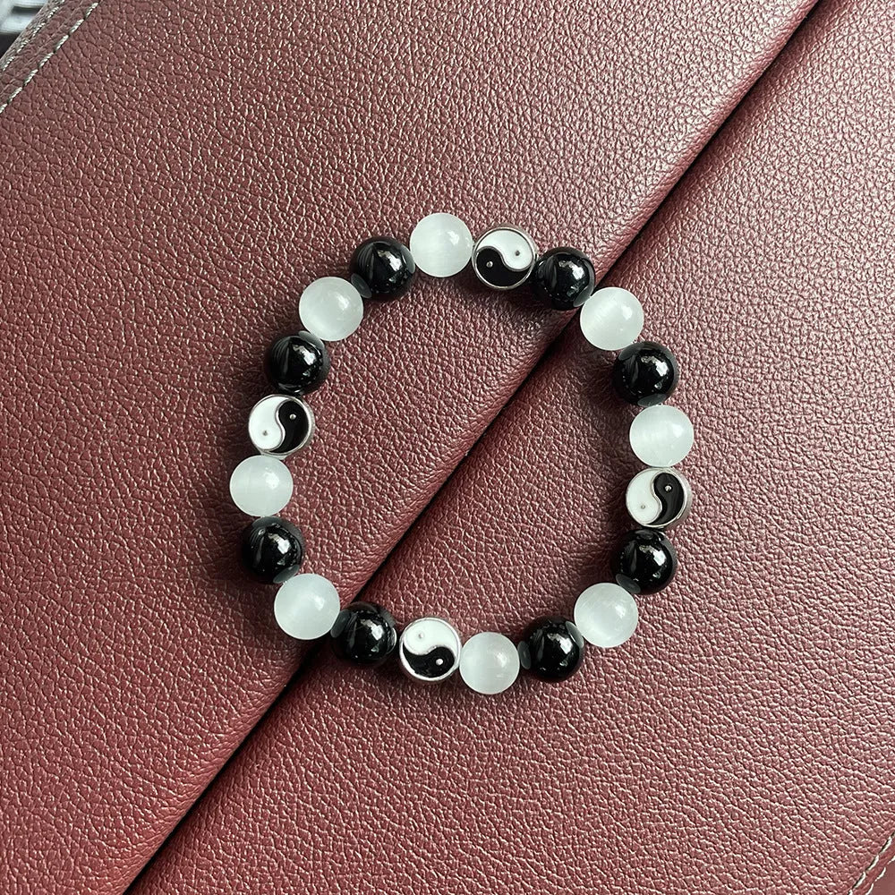 Opal and black agate Tai Chi bracelet with 10mm polished stone beads on a wrist.