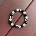 Opal and black agate Tai Chi bracelet with 10mm polished stone beads on a wrist.