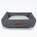 Square grey linen dog bed on a wooden floor for autumn and winter.
