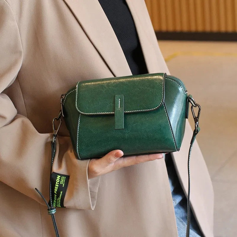 Brown women's genuine leather messenger bag with cross-body strap, showing outer sandwich pocket and visible sewing detail.