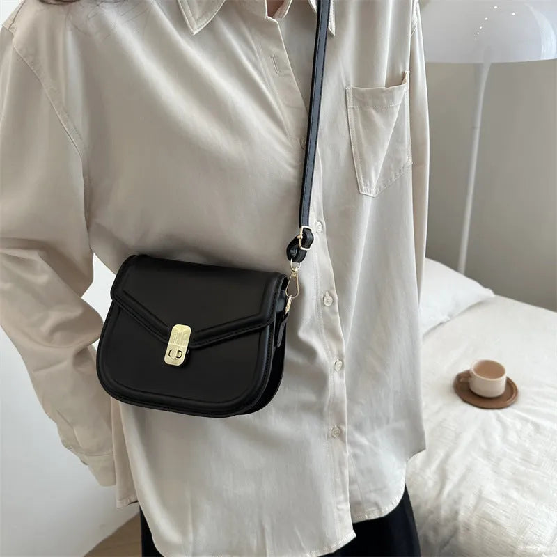 Men's soft black PU leather clamshell messenger bag in a horizontal square shape on a table.