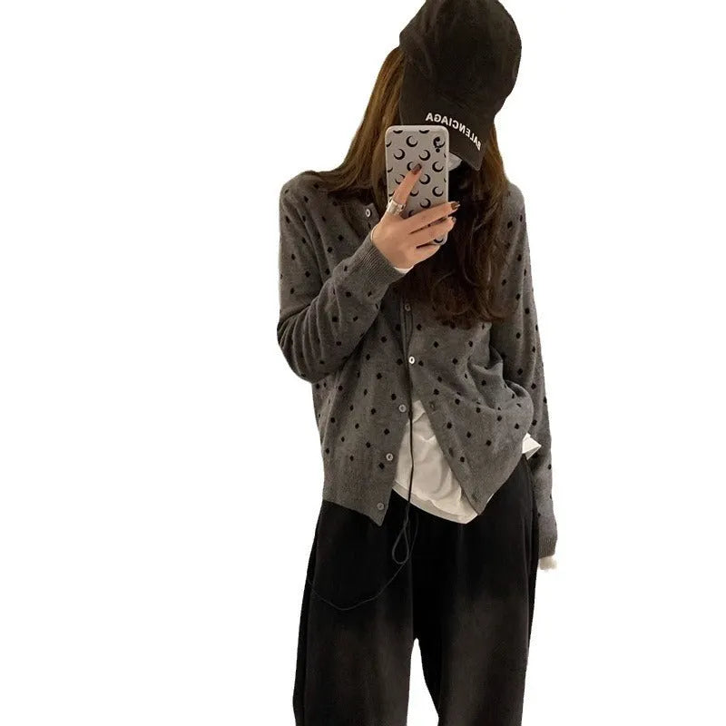 Women's grey dot patterned knitted cardigan with crochet flower detail on sleeve.