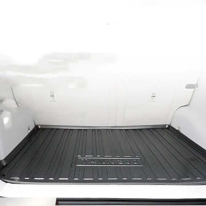 Black TPE car boot liner with carbon fibre pattern texture, shown fitted in a vehicle trunk.