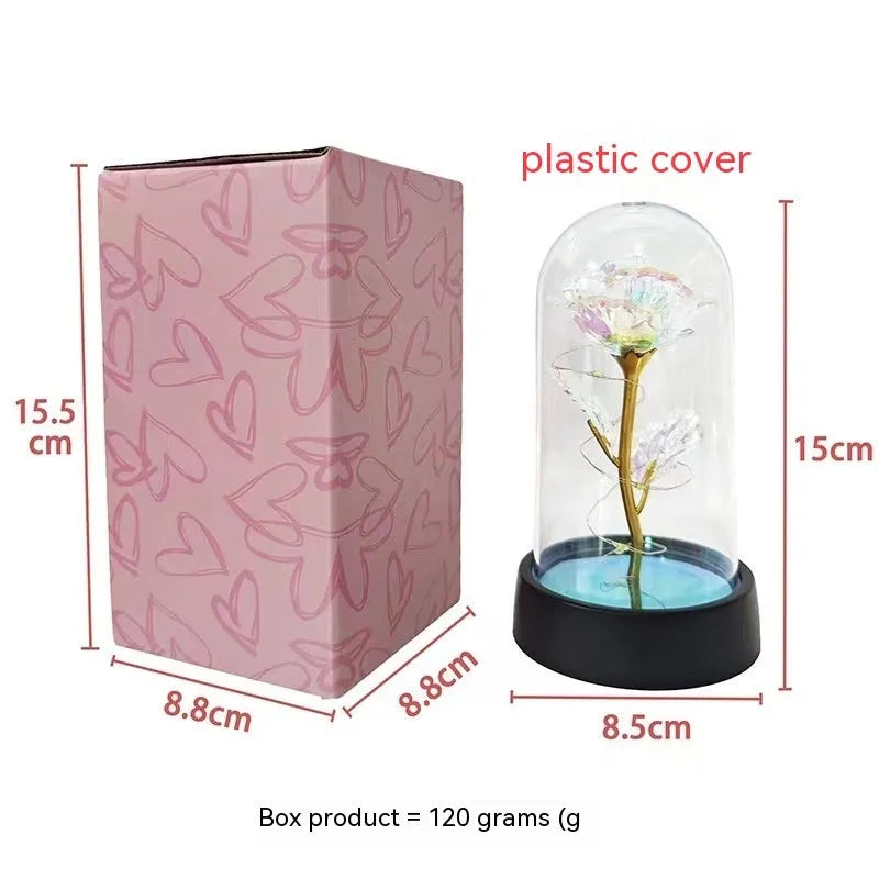 Small decorative night lamp with glass cover and plastic flowers, showing coloured light illumination.