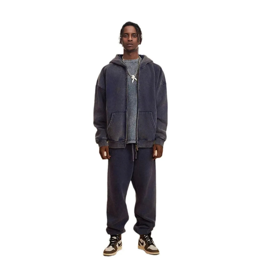 Man wearing a dark green fleece-lined hooded cardigan sweater with a double zipper.