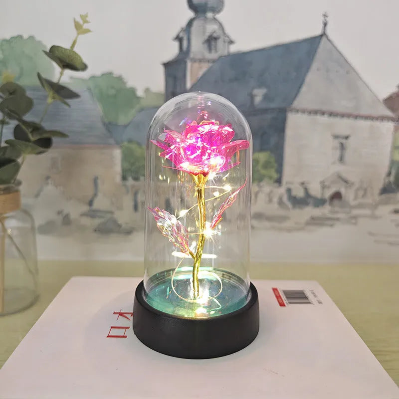 Small decorative night lamp with glass cover and plastic flowers, showing coloured light illumination.
