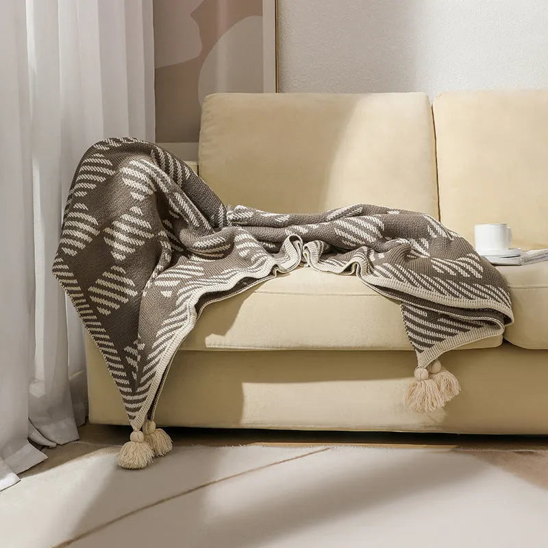 Acrylic sofa blanket with tassel fringe in neutral beige tone on grey sofa