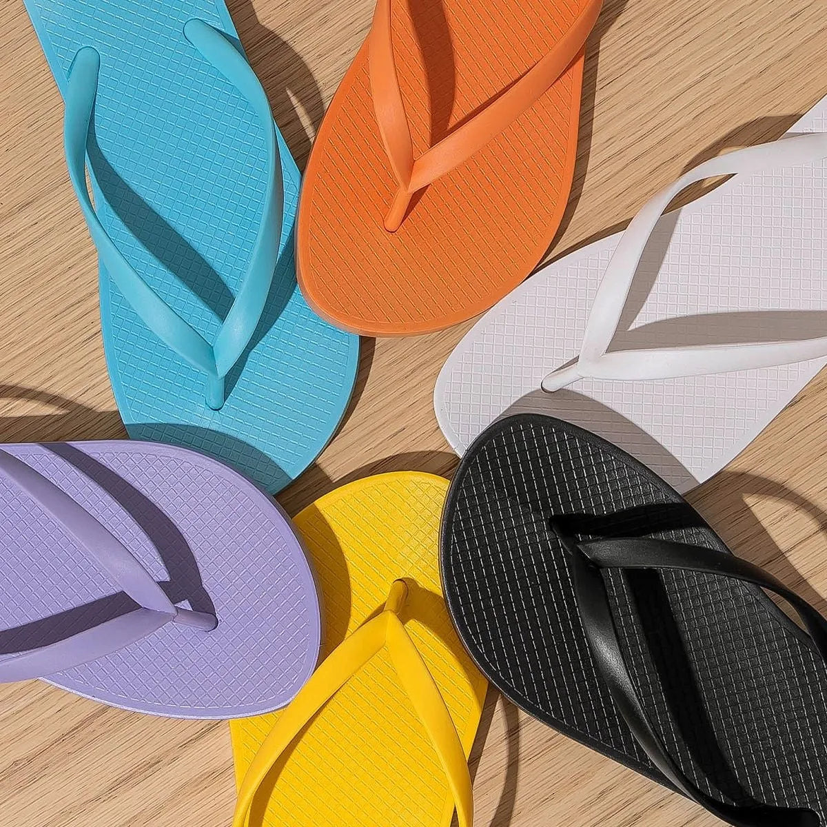 Orange foldable beach slippers with non-slip soles shown next to a pair in purple and black.