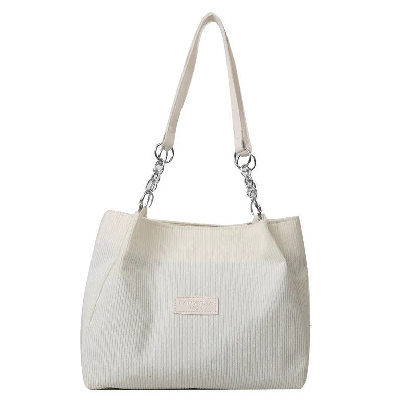 Corduroy one-shoulder tote handbag in black, showing three-dimensional pockets and a large main compartment.