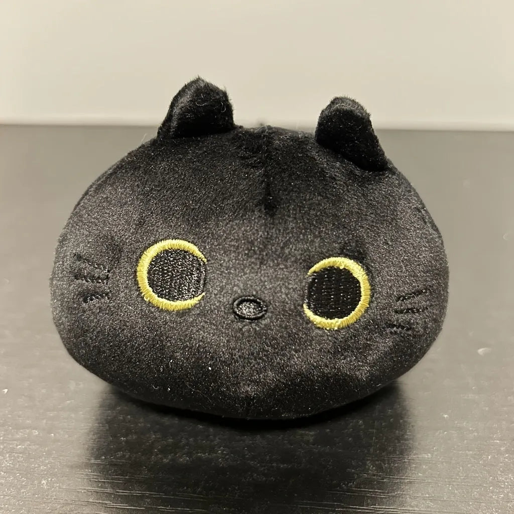 Fluffy black cat plush toy used as a soft pillow cushion on a sofa.