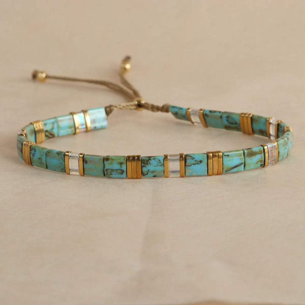 Geometric glass beaded bracelet in milky white, black, green, blue, or red on a white background.