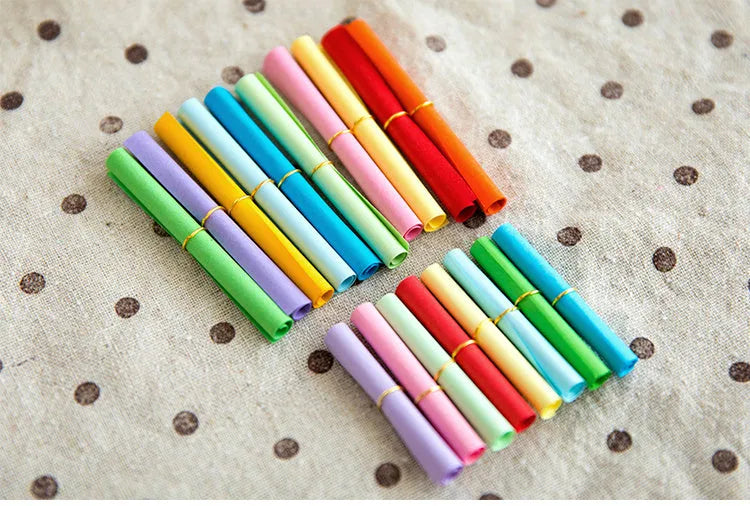 Assortment of colourful mini paper scrolls with metal eyelets for drift bottle messages and crafts.