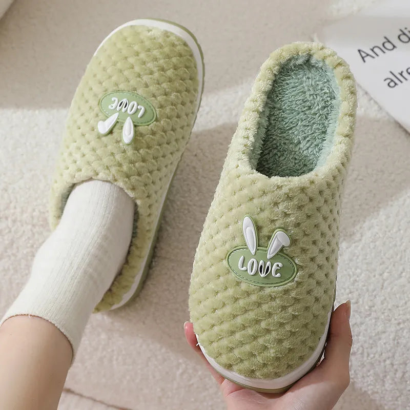 Women's plaid design artificial fur winter slippers with rubber sole on a wooden floor.