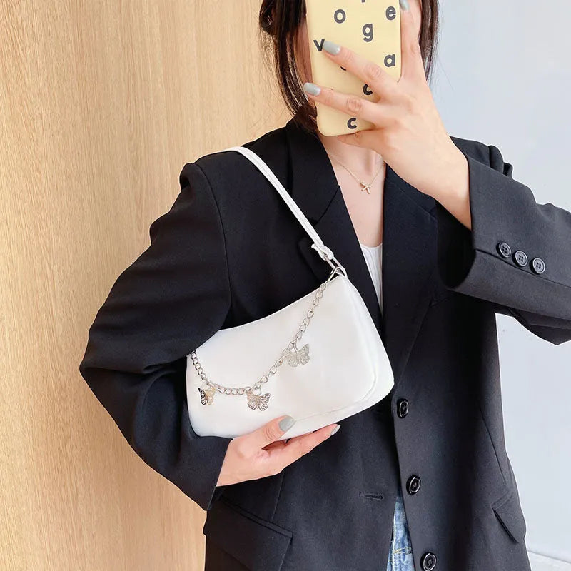 Women's black butterfly chain underarm bag with crossbody strap, showing structured square shape and retro style.