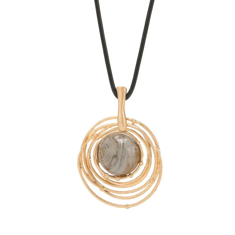 Gold geometric alloy pendant on a brown snakeskin wax rope chain necklace laid flat.
