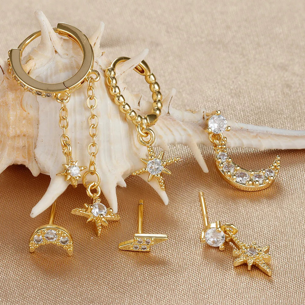 Set of six gold chain tassel drop earrings with crystal studs on a white background.