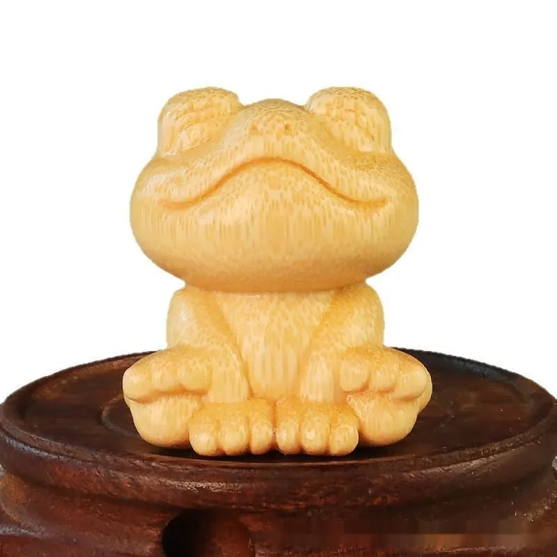 Solid bamboo carving ornament of a smiling frog cartoon character.