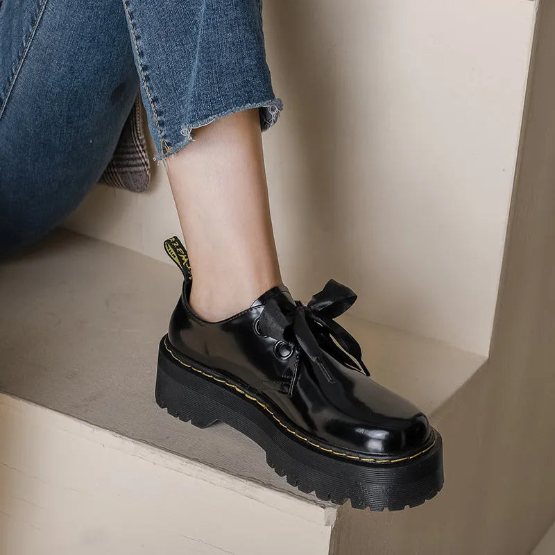 Women's black leather shoes with thick sole, cross strap, and ribbon lacing closure