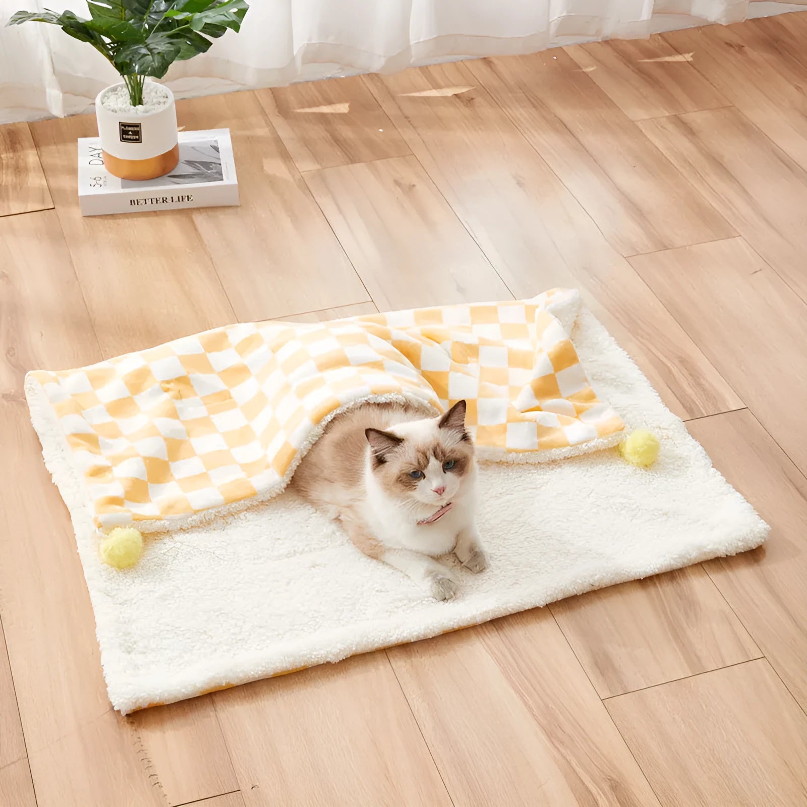 Green plaid plush fleece pet blanket with fur ball trim, laid flat as a dog bed or cat mat.