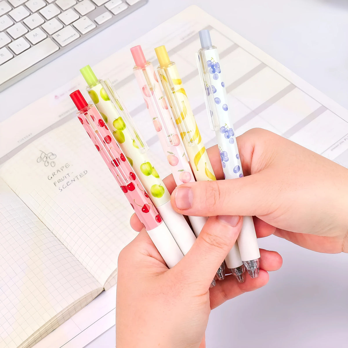 Three fruit-scented press-action pens with plastic barrels and black 0.5mm refills.