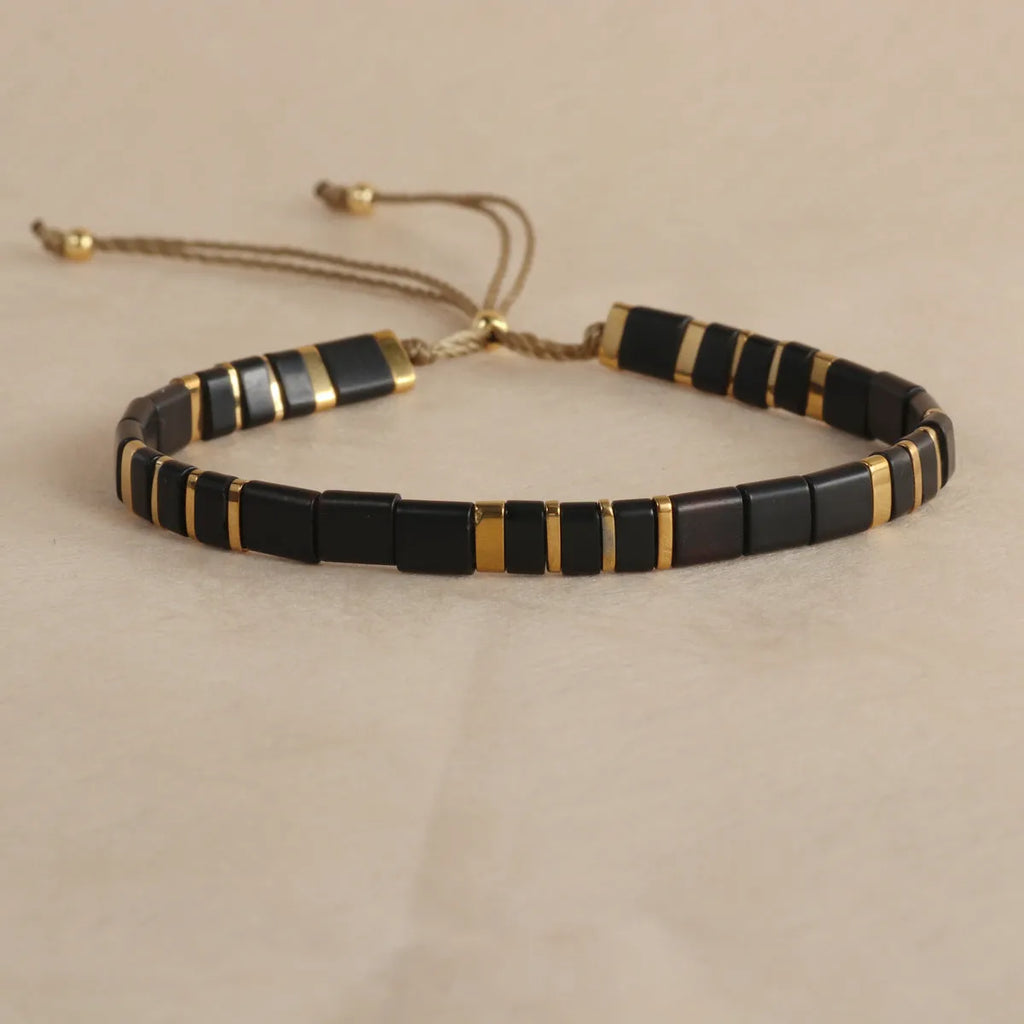 Geometric glass beaded bracelet in milky white, black, green, blue, or red on a white background.