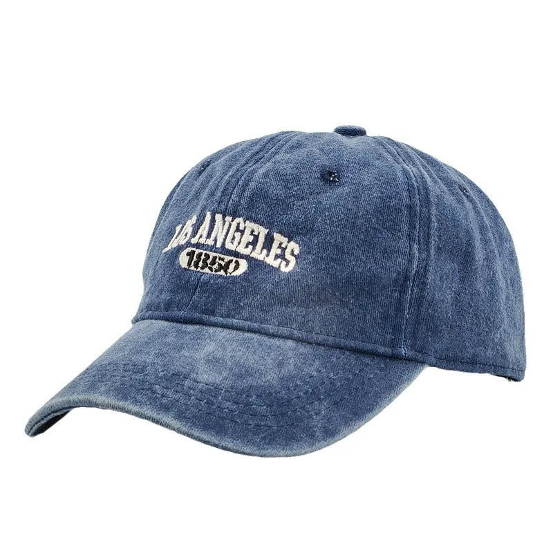 Retro style peaked cap with embroidered distressed letters on the front, shown in beige colour.